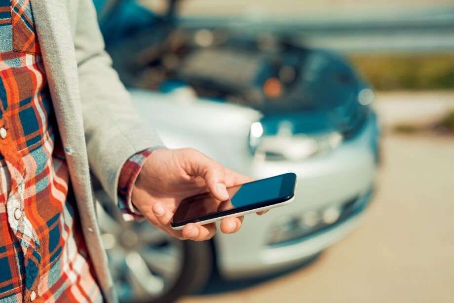 A man accesses his parking permit from his phone while standing by his car